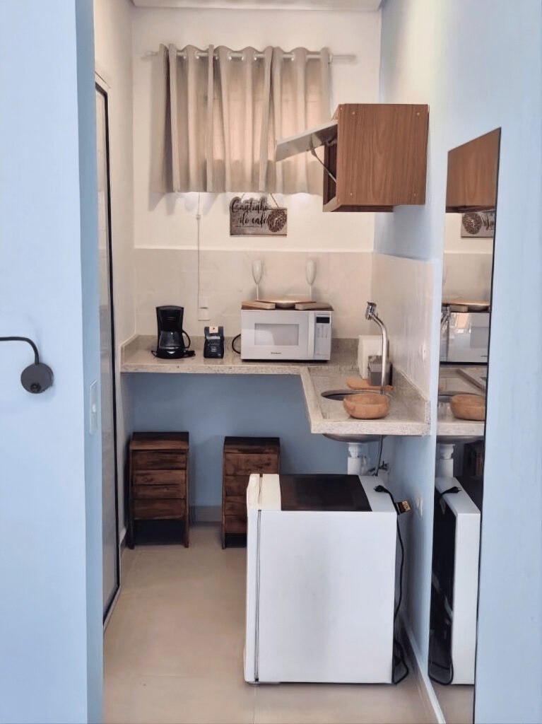 Mini copa equipada do studio com frigobar, pia de granito, micro-ondas e balcão.