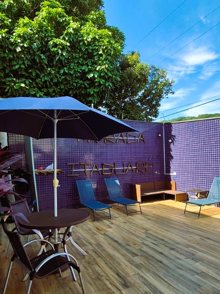 Deck com espreguiçadeiras e guarda-sol na área da piscina da Morada Itaguaré.